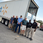 A group of people standing in front of a truck.